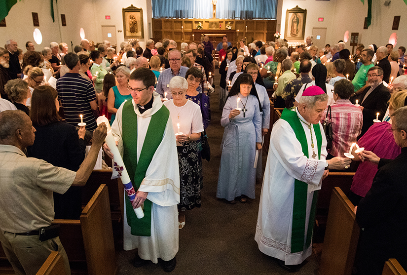 Archbishop Carlson lit candles of participants of a Faith in Ferguson session in 2015 at Our Lady of Guadalupe Church in Ferguson. The prayer service was held for the one-year anniversary of the death of Michael Brown.