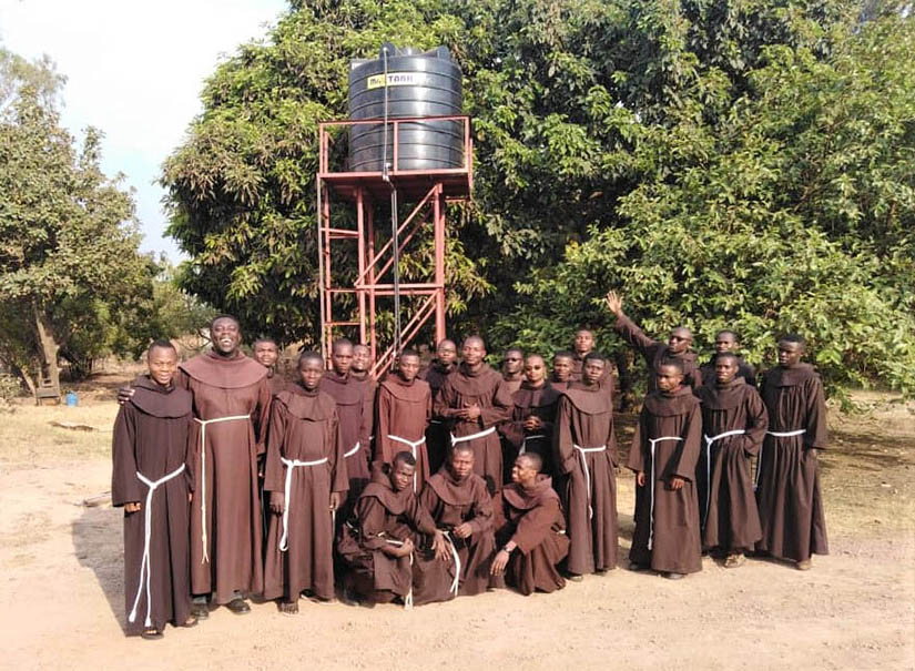 Franciscan friars from the novitiate in Lubumbashi, Democratic Republic of Congo, gathered in front of a well that the parishioners at St. Margaret Mary Alacoque helped to fund. Franciscan Charities, based in St. Louis, has funded eight water projects in the African nation.
