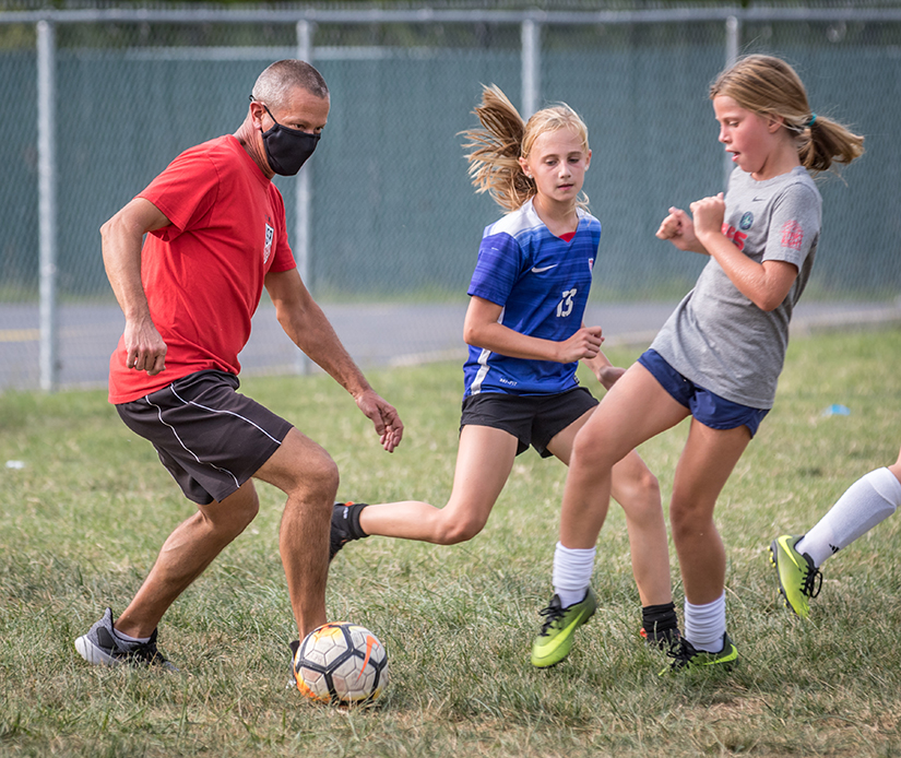 Coach Brad Brown played with Emery Fernandez, center, and Lily Greffet, right, during the girls fifth-grade soccer practice at St. Catherine Laboure Parish Sept. 15. CYC teams in St. Louis County will begin playing games with limited spectators and other health guidelines.
