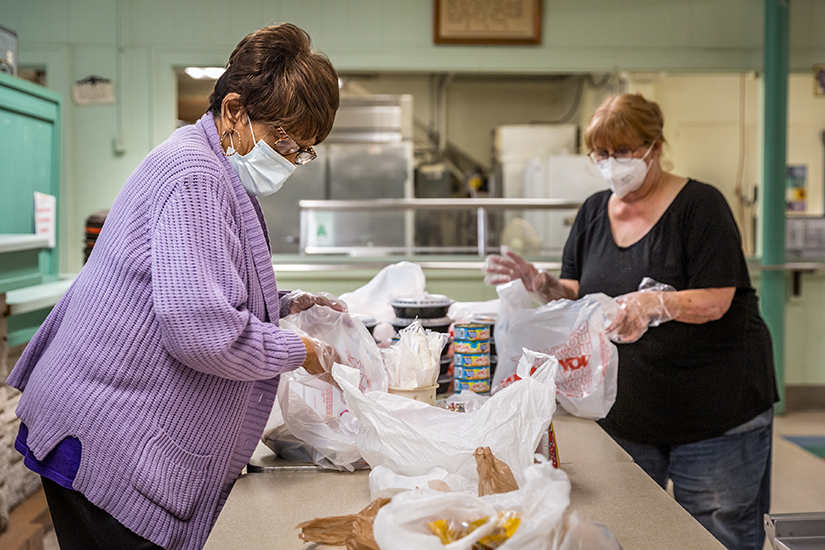 Ollie Shaw, left, and Jan Quinn put together bag lunches at Our Lady of the Holy Cross Senior Resource Center. The program received a grant from the Catholic Campaign for Human Development and is reaching out to people during the COVID-19 pandemic.