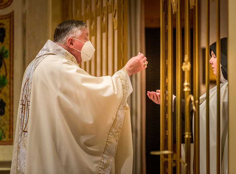 Archbishop Mitchell Rozanski distributed the Eucharist to Sister Gemma Rose as he celebrated Mass for the Discalced Carmelite nuns at the Carmel of St. Joseph in Ladue Nov. 19.