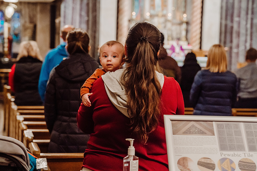 A baby is seen during Ash Wednesday Mass at St. Aloysius Church in Detroit Feb. 17 amid the coronavirus pandemic. Experts say churches should begin planning now to welcome back parishioners after the pandemic is over.