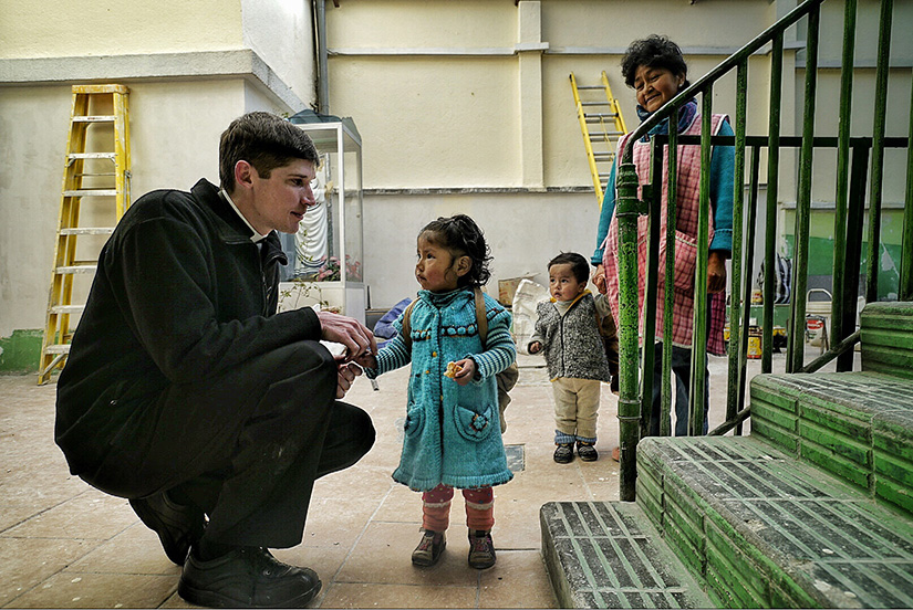Father Timothy Noelker talked to a little girl as she arrived to the day care at the Missionaries of Charity. Father Noelker served in the Latin America Apostolate in Bolivia for five years, before becoming director of the archdiocesan Mission Office.