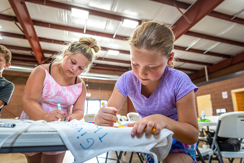 Sophia Randolph and Grace Arnold, fourth graders at St. Rose of Lima in De Soto, designed aprons with eucharistic themes during Vacation Bible School at the parish July 15.