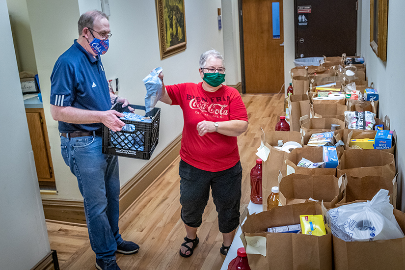Vincentian Father Dan Theiss worked in the food pantry with parishioner Mary Curran preparing bags of groceries for clients at St. Vincent de Paul Parish in St. Louis Aug. 23.