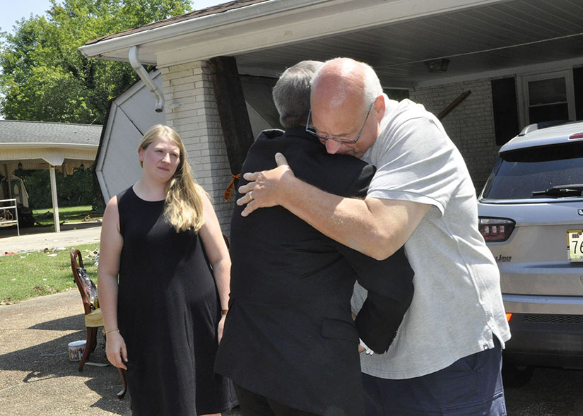 Bishop J. Mark Spalding of Nashville, Tenn., embraced Henry Kersten outside his home in Waverly, Tennessee, Aug. 24. Kersten’s wife, Leslie, was killed by the Aug. 21 flood. Also pictured is Joanne Dashiell, Kersten’s daughter.
