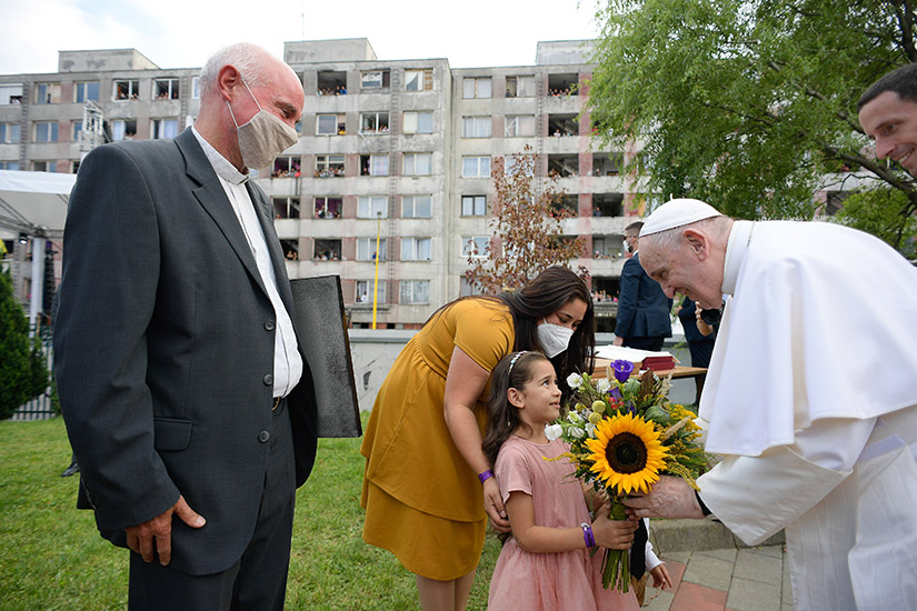 Pope Francis accepts flowers from a girl during a meeting with the Roma community in the Luník IX neighborhood in Košice, Slovakia, Sept. 14.