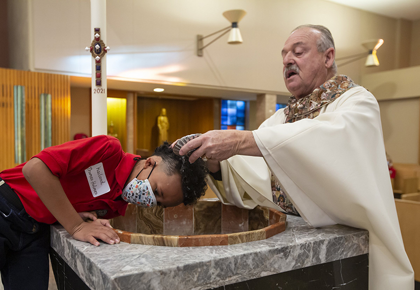Msgr. Vincent Bommarito baptized Kailand Thomas-Holmes, 7, and two other students from South City Catholic Academy on Oct. 20. The baptism was celebrated during an all-school Mass at St. Joan of Arc Church.