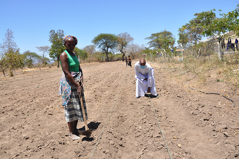 Father Patrick Ndonga helps set up drips lines in St. Stephen Catholic Mission farm in Yathui, Kenya, Oct. 27, to irrigate crops in the dry area. The farm produces food for the parish school and the surplus is sold to the community, with some given to the poor. 