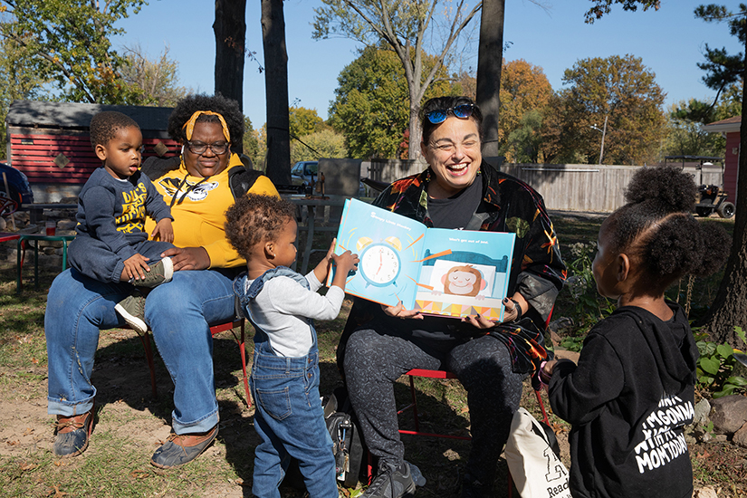 Sheila Oliveri, center, read a story to children at A Red Circle’s Healthy Mom and Babies bonfire event at the Rustic Roots Sanctuary in Spanish Lake on Nov. 6. The Catholic Campaign for Human Development has granted A Red Circle $10,000 for its Healthy Food Access program aimed at improving food access in north St. Louis County. From left, Jeremiah Keeble, 2, his mom Chiquita Keeble, La’Mariel Ivy, 2, Oliveri, and Ava Coleman, 2, listened to the story.