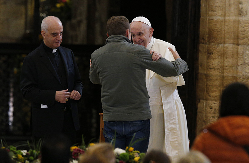Pope Francis embraced a man during a meeting with the poor at the Basilica of St. Mary of the Angels in Assisi, Italy, Nov. 12. The visit was in preparation for the celebration of the World Day of the Poor. Also pictured is Archbishop Rino Fisichella, president of the Pontifical Council for Promoting New Evangelization.