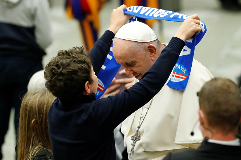 A boy gave Pope Francis a scarf of the Pavia soccer club at the weekly general audience in the Paul VI hall at the Vatican Nov. 17.