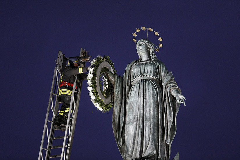 A firefighter placed a wreath on a tall Marian statue overlooking the Spanish Steps in Rome Dec. 8, the feast of the Immaculate Conception. Pope Francis prayed at the statue before daybreak, continuing the papal tradition of visiting the Spanish Steps on the feast.