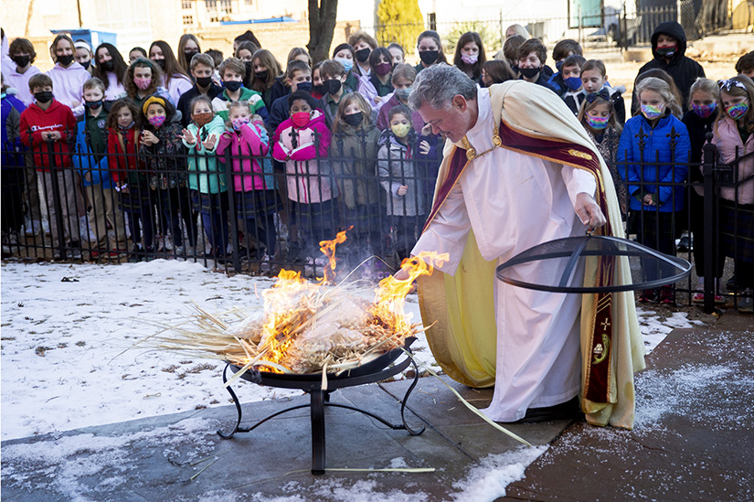 Father Jack Siefert, pastor of St. Ambrose Parish, burned palms as school students watched Feb. 28. The palms were distrubuted on Palm Sunday last year, and the ashes were mixed with oil, blessed and distributed on Ash Wednesday.
