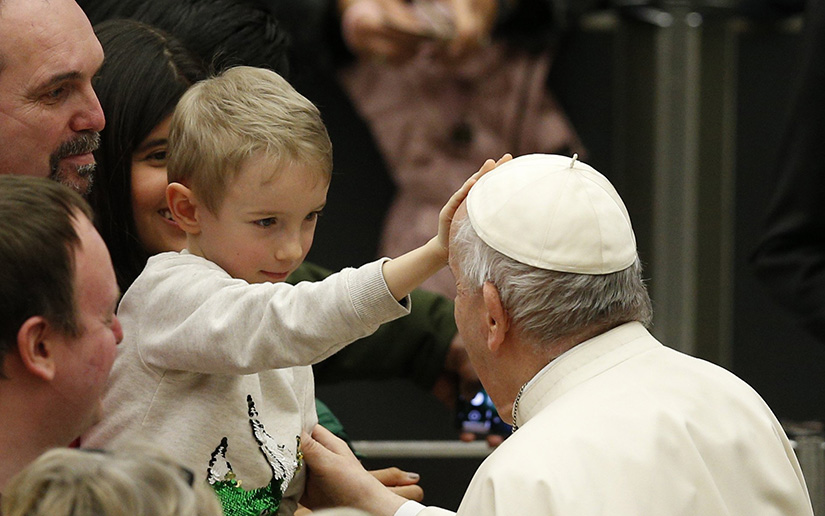 A boy touched Pope Francis’ head during the general audience in the Paul VI hall at the Vatican March 2. In his catechesis, the pope continued talking about the meaning and value of old age and the relationship between the young and the old.