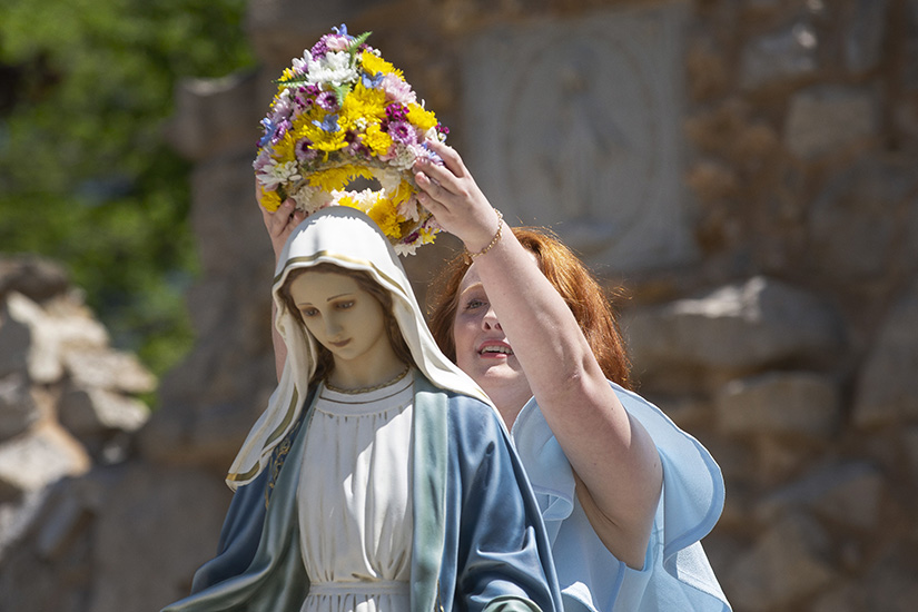 Claudia Otte, a senior at St. Vincent de Paul High School in Perryville, crowned a statue of Mary on May 1 at the grotto on the grounds of the National Shrine of Our Lady of the Miraculous Medal in Perryville.