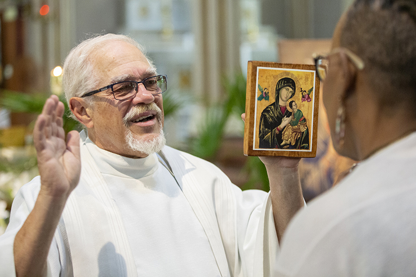 Redemptorist Father Rodney Olive, associate pastor at St. Alphonsus Liguori “Rock” Church, blessed parishioner Roberta George while holding an icon of Our Mother of Perpetual Help on May 31 at the Rock Church in St. Louis. The parish is celebrating the 100th anniversary of hosting weekly devotions to Our Mother of Perpetual Help on Tuesdays.