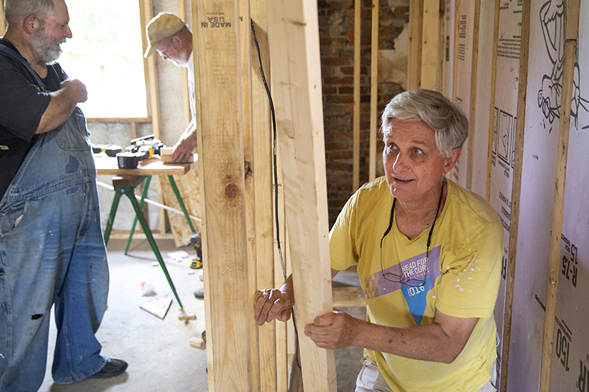 Volunteer Jim Garrone, a parishioner at Ascension Church in Chesterfield, carried a piece of wood as fellow volunteers Bob Schuchmann, left, and Bob Bachmann, worked on June 1. The volunteers were working on a house on Fall Avenue in St. Louis that is being rehabbed by North Grand Neighborhood Services.
