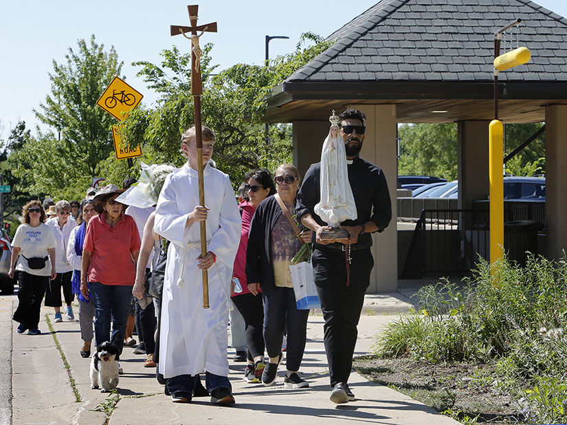 Father Hernan Cuevas carried a statue of Mary as parishioners from Immaculate Conception and St. James Parish processed July 9 near the site of the July 4 mass shooting in Highland Park, Ill.
