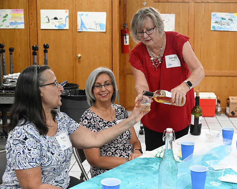Sandy Timpe poured a glass of wine for an attendee at the Women at the Well Syrian Supper Club event at St. Gabriel Parish July 19.
