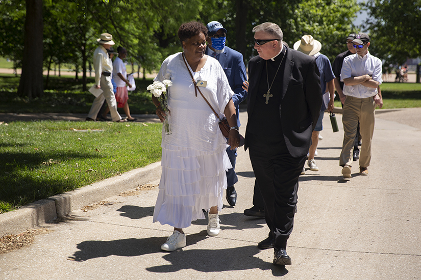 Joyce Jones, left, director of the Office of Racial Harmony with the Archdiocese of St. Louis, with Archbishop Mitchell T. at the inaugural Forgive Us Our Trespasses prayer service and Maafa procession June 18 on the grounds of the Gateway Arch near the Old Cathedral in St. Louis. A Maafa is a traditional procession memorializing lives lost during the Middle Passage of the Atlantic slave trade.” 