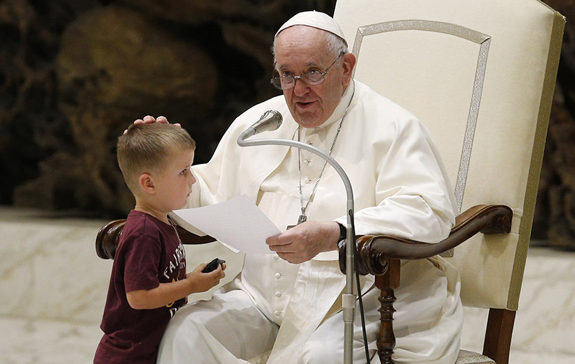 Pope Francis greeted a boy who ran onstage during his general audience in the Paul VI hall at the Vatican Aug. 17. “During the audience we talked about dialogue between old and young, right? And this one, he has been brave and he’s at ease,” the pope said about the boy.