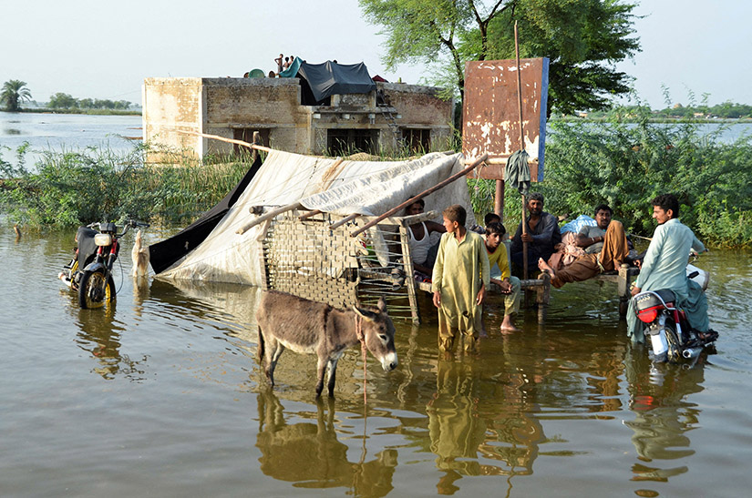 People waded in floodwaters outside their home following heavy rains during the monsoon season in Sohbatpur district of Pakistan.