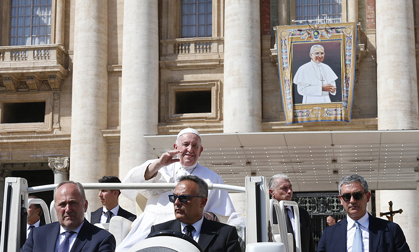 Pope Francis greeted the crowd as he left his general audience in St. Peter’s Square at the Vatican Sept. 7. In the background is a banner on St. Peter’s Basilica depicting Blessed John Paul I, who was beatified by Pope Francis Sept. 4.