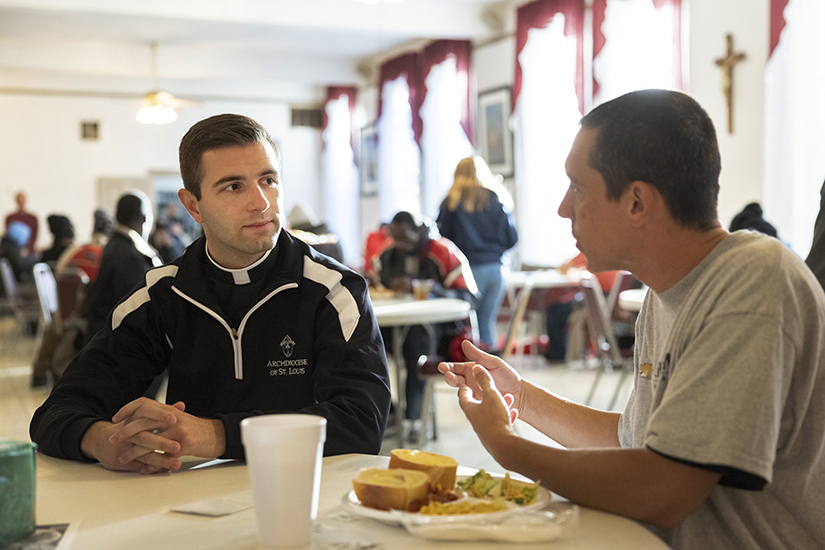 Transitional deacon Ryan Quarnstrom spoke with Kaiden Lee Cash during a meal service in October at Sts. Peter and Paul Parish Hall in St. Louis. The meals program has free meals served daily from the 2nd to 21st of each month. 
