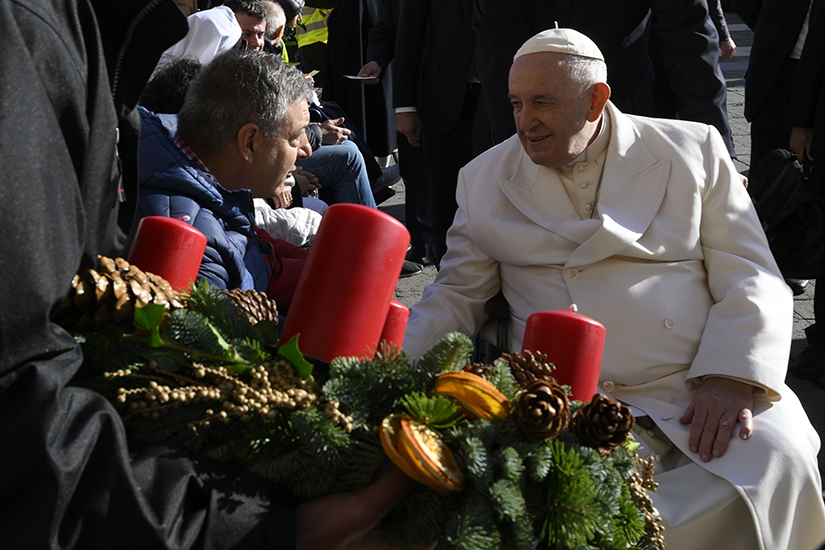 Pope Francis greeted a man while another person held an Advent wreath for the pope to bless at the end of his weekly general audience Nov. 23 in St. Peter’s Square.