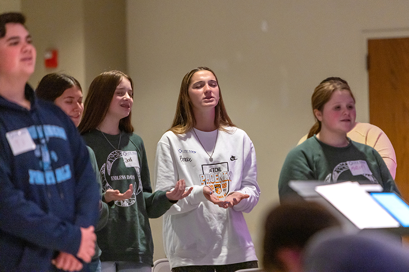 Brooke Tufts, right, prayed and sang during a Life Teen gathering at Assumption Church in O’Fallon Dec. 4.