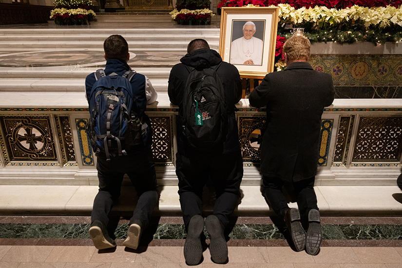 Churchgoers prayed near an image on Pope Emeritus Benedict XVI following a memorial Mass for the late pope Jan. 5 at the Cathedral Basilica of Saint Louis in St. Louis. Pope Emeritus Benedict XVI died Dec. 31, 2022, at 95 years old.