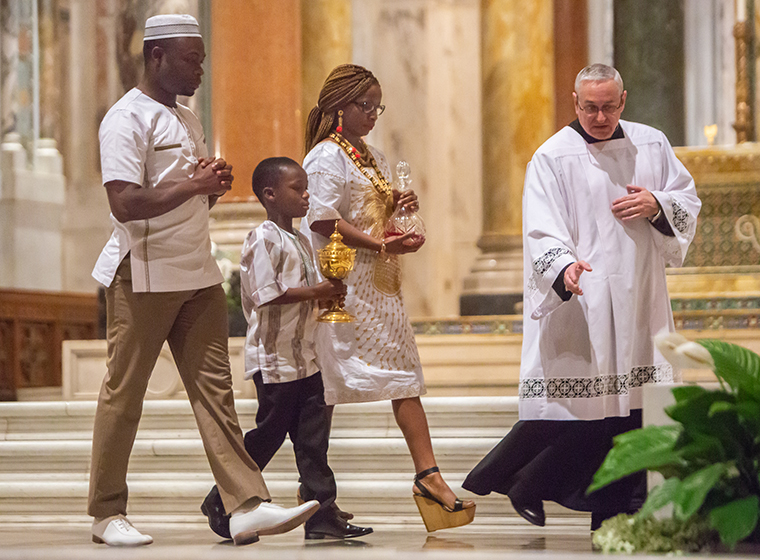 Father Nicholas Smith led the Kombey family — from left, Medard, Penouel and Felicity — as they offered the gifts at a multicultural Mass at the Cathedral Basilica of Saint Louis on May 23. Bishop Mark S. Rivituso celebrated the Mass with readings, universal prayers and music in several languages and signed by an interpreter. The Kombeys are parishioners at Christ the King Parish in University City.