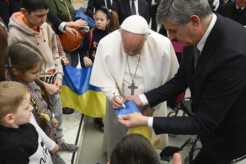 Pope Francis signed a Ukrainian flag for a Ukrainian child at the end of his weekly general audience Feb. 22 in the Vatican audience hall. During the audience, the pope noted the Feb. 24 anniversary of Russia’s invasion of Ukraine and prayed for an end to the war.