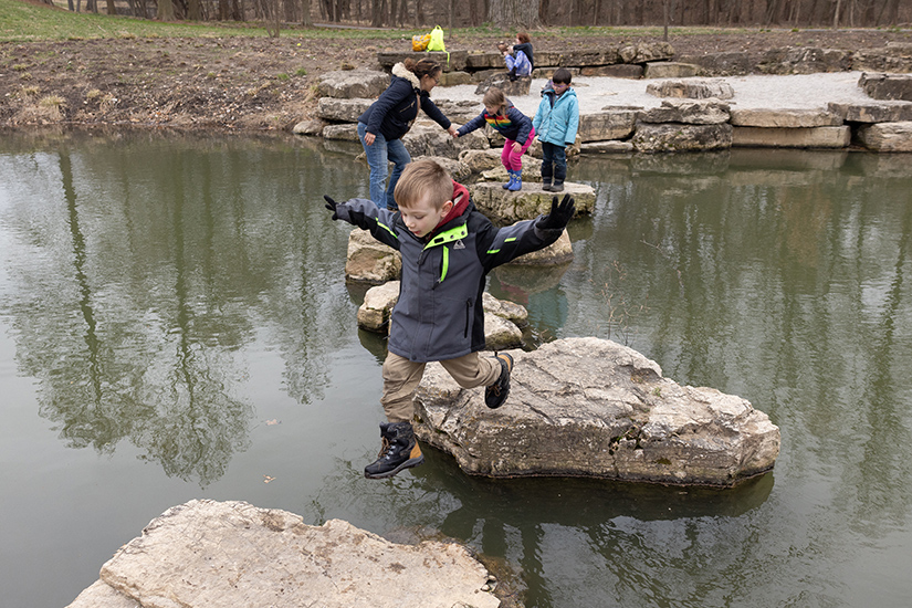 Marcus McDonough jumped to a rock during a Wilderkids Urban Forest School’s spring break camp on March 21 at Forest Park in St. Louis. The camp helps children get to know and love the Earth and, by doing so, learn to care for creation.