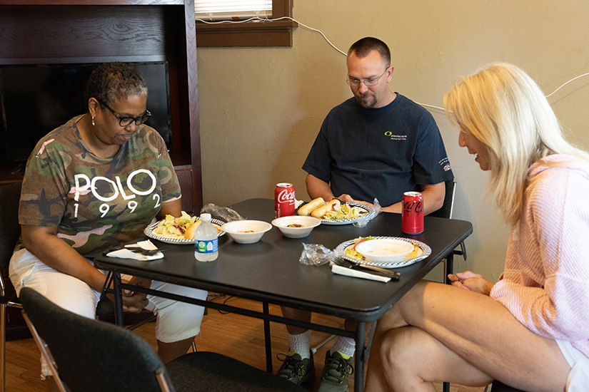 From left, TaWanda Johnson, a case manager with Criminal Justice Ministry, Andy Bullard, who was recently released from prison, and Kelly Bulanda, a volunteer with Criminal Justice Ministry, prayed before a meal May 23 at Andy’s home in St. Louis.
