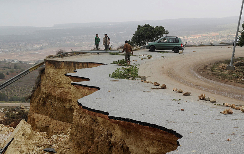 People stood on a damaged road as a powerful storm and heavy rainfall flooded hit Shahhat city, Libya, Sept. 11. At least 5,100 people have died and 10,000 are believed missing after Storm Daniel dumped so much rain on Libya’s northeast that two dams collapsed sending water flowing into already inundated areas.