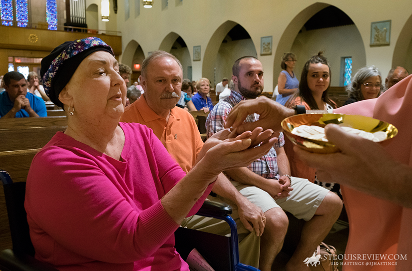 Cancer patient Mary Callahan received Communion at the Mass at St. Mary Magdalen Church in Brentwood. Callahan, who is undergoing her third bout with breast cancer, gestured to her family seated next to her at a reception after Mass and said, “these people are going to help me though this.”