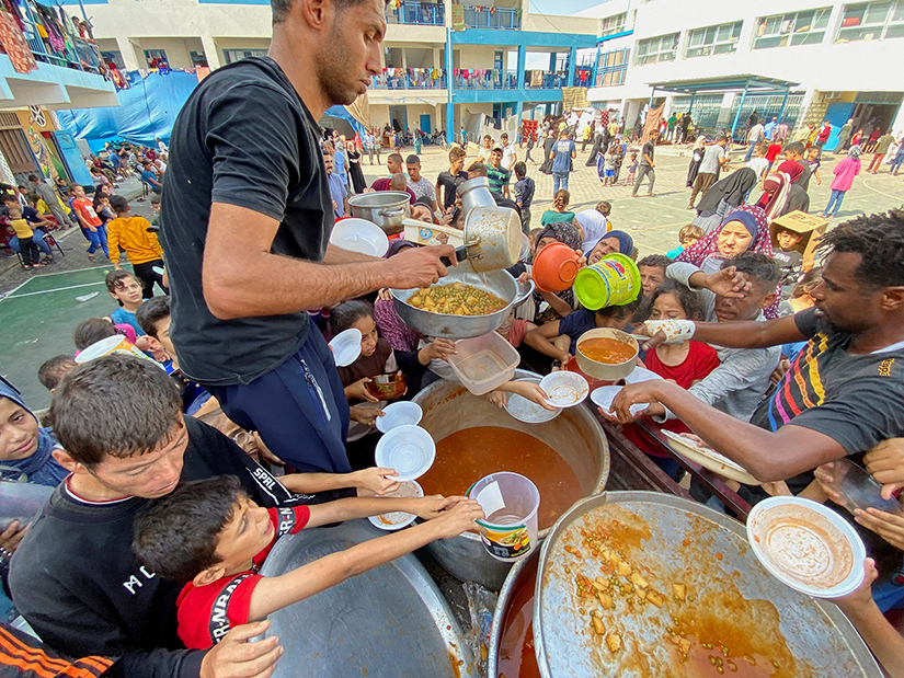 Palestinians who fled their houses due to Israeli airstrikes gathered Oct. 23 to receive food offered by volunteers at a U.N.-run school where they have taken taken refuge in Rafah, in the southern Gaza Strip.