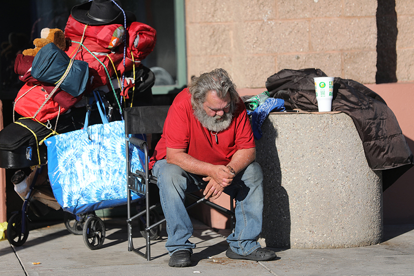 A homeless man sat with his belongings outside a shopping center in Tucson, Ariz., Oct. 22.