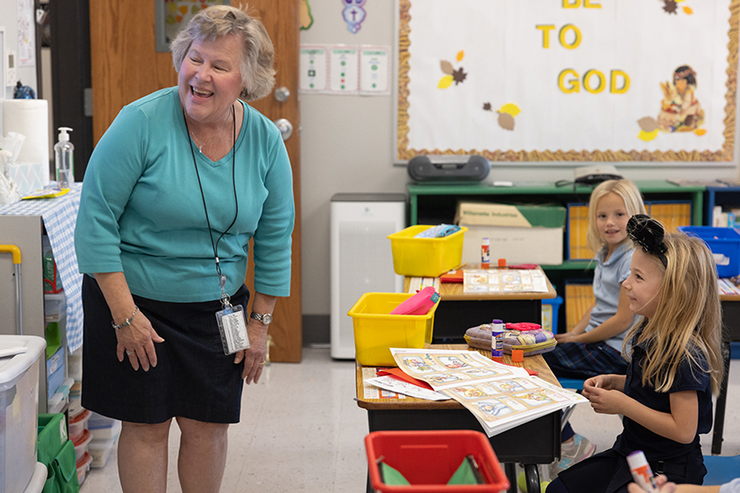 Kindergarten teacher Lori Aholt smiled while instructing students, including Madelyn Straatmann, foreground, and Callie Connor on Nov. 16 at Our Lady of Lourdes School in Washington. Aholt is one of six teachers at Catholic schools in the archdiocese to be honored with an Emerson Excellence in Teaching Award.