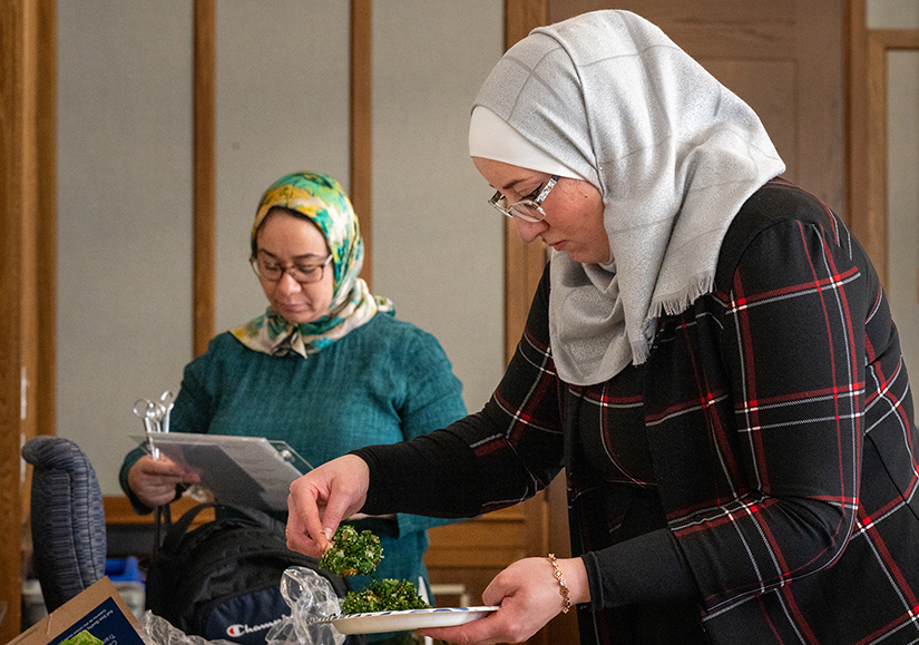Mawda Altayan, right, a Syrian chef working with the Supper Club program at Welcome Neighbor STL, prepared a plate during a Syrian meal at the Global Table discussion lunch on Nov. 15 at the Brown School of Social Work at Washington University in St. Louis. Supper Club events feature meals prepared by refugee chefs who also share insights about their countries of origin. Welcome Neighbor STL has received a $10,000 economic development grant from the Catholic Campaign for Human Development and plans to use the funds to develop a business plan and pilot program for a Supper Club food truck.