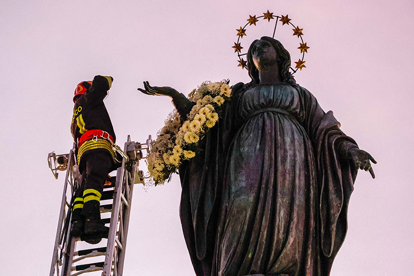 A firefighter saluted Mary after placing a wreath of flowers on a statue near the Spanish Steps in Rome Dec. 8, the feast of the Immaculate Conception. Pope Francis prayed at the statue later in the day, continuing the papal tradition of visiting the Spanish Steps on the feast of the Immaculate Conception.