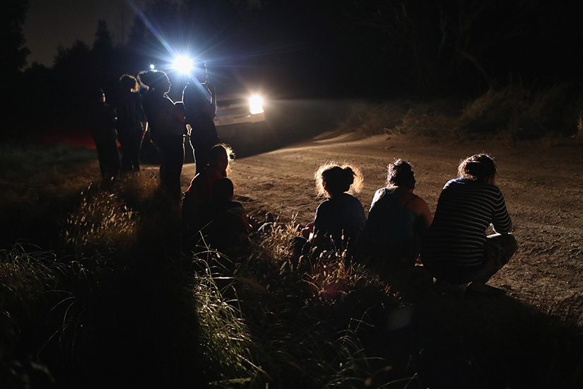 A U.S. Border Patrol vehicle illuminated a group of Central American asylum seekers before taking them into custody near the U.S.-Mexico border on June 12 in McAllen, Texas. The group of women and children had rafted across the Rio Grande from Mexico and were detained by U.S. Border Patrol agents before being sent to a processing center for possible separation.
