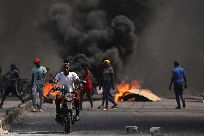 A man drove past a burning barricade during a protest against Haitian Prime Minister Ariel Henry’s government and insecurity in Port-au-Prince March 1.