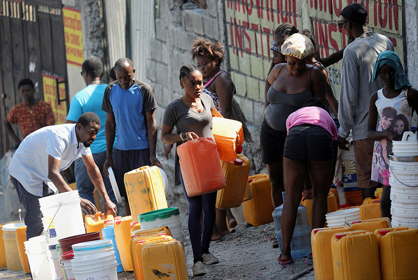 People waited along a street to collect water in buckets and containers amid recent violence in Port-au-Prince, Haiti, March 12. Haitian Prime Minister Ariel Henry pledged to resign March 11.