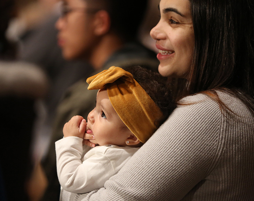 A woman held her daughter during Mass Jan. 19, 2023, at the Basilica of the National Shrine of the Immaculate Conception in Washington. Organizers of this summer’s National Eucharistic Congress in Indianapolis said that in addition to accommodations for families with young children, there will also be specific programming to engage families and children together.