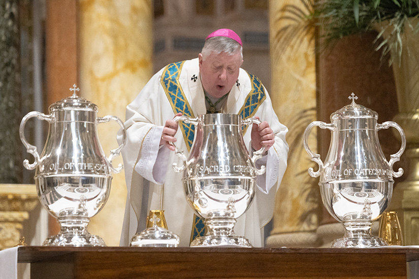 Archbishop Mitchell T. Rozanski breathed in a vessel containing balsam and olive oil during the consecration process for making sacred chrism during the Chrism Mass on Holy Thursday, March 28, at the Cathedral Basilica of Saint Louis. 