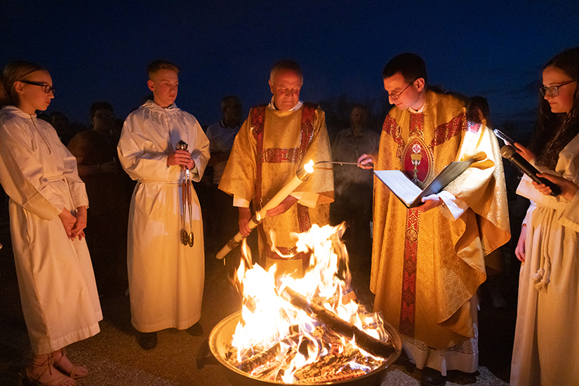 Father Michael Lampe lit the paschal candle held by Deacon Neal Westhoff at the start of the Easter Vigil on March 30 at Immaculate Conception in Old Monroe.