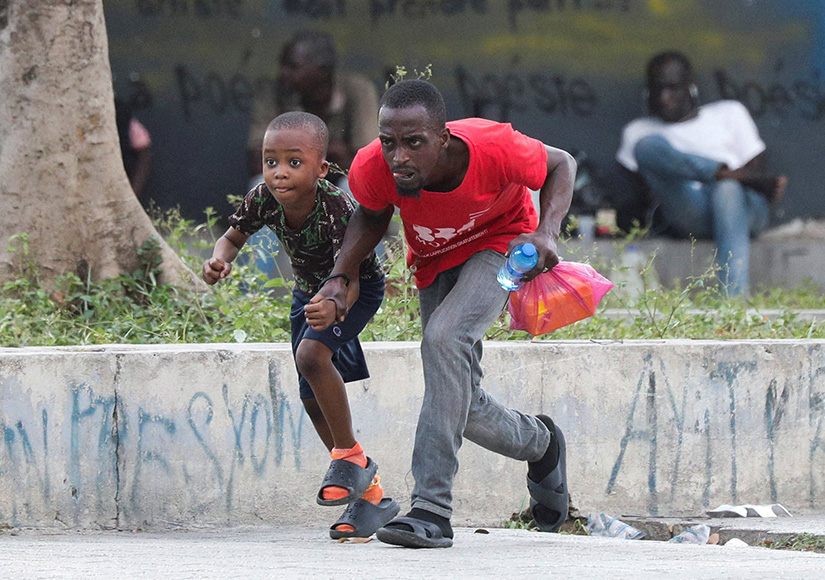A man and child took cover from gunfire near the National Palace in Port-au-Prince, Haiti, March 21.